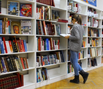 Uma estudante procurando por livros em uma estante na biblioteca da universidade