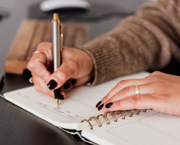 Uma mulher escrendo em um caderno