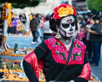 Uma mulher vestida com uma fantasia de caveira em uma feira à ceu aberto